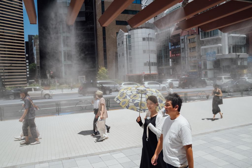 2022年6月26日，行人走过日本街头的喷水消暑装置。(新华社记者张笑宇